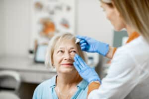 Female,Doctor,Dripping,Eye,Drops,On,Eyes,Of,A,Senior